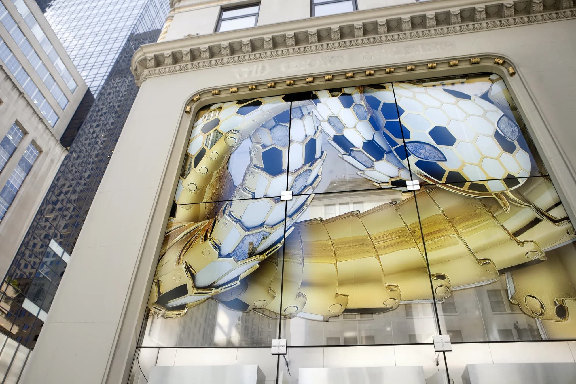 Upward view of a Bulgari window arch filled with a gold and navy Serpenti scale graphic