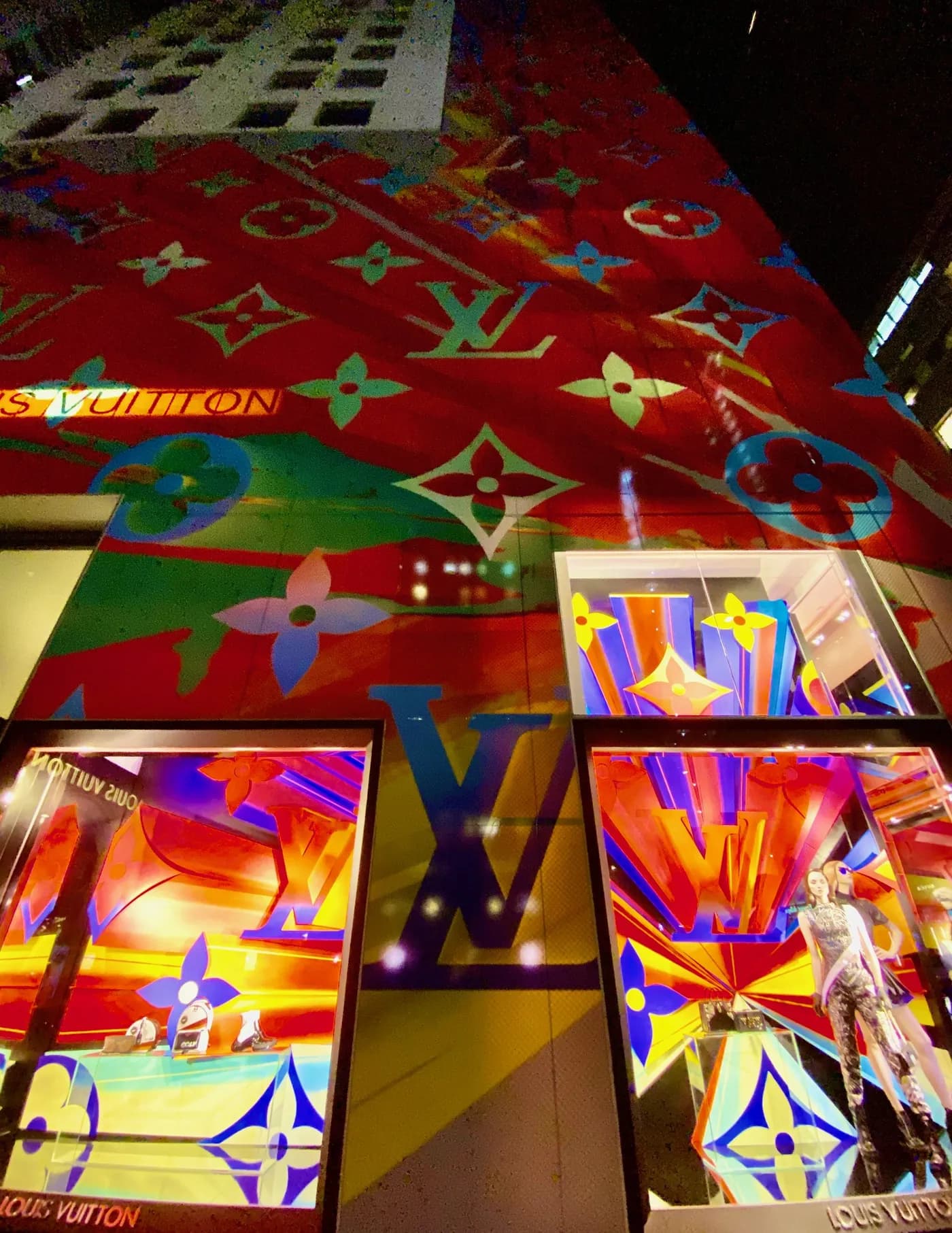 Close-up of a multicolor Louis Vuitton monogram facade wrap above lit windows