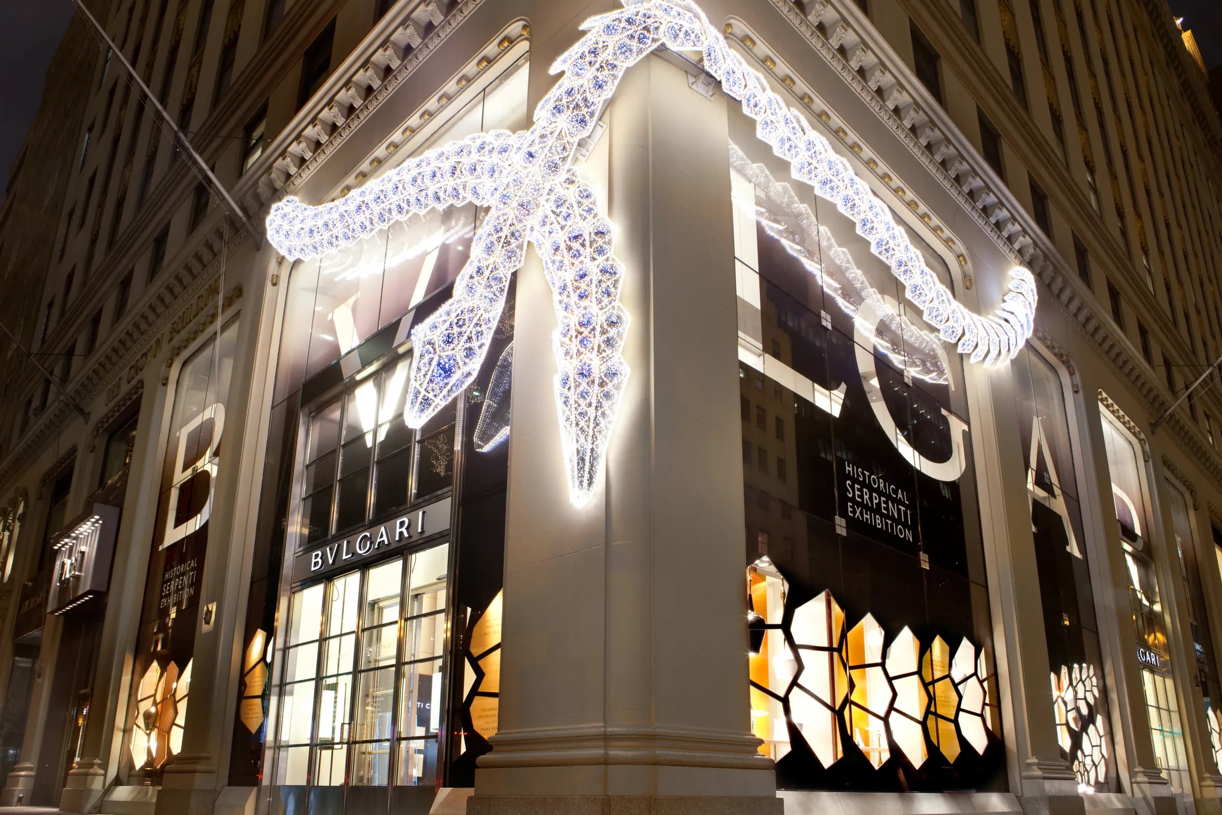 Bulgari facade at night with an illuminated serpent sculpture and oversized window lettering