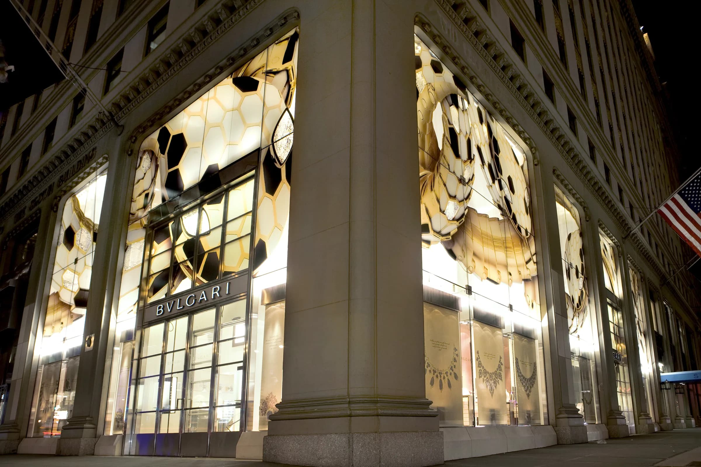 Bulgari flagship corner at night with windows filled by glowing oversized Serpenti scale graphics