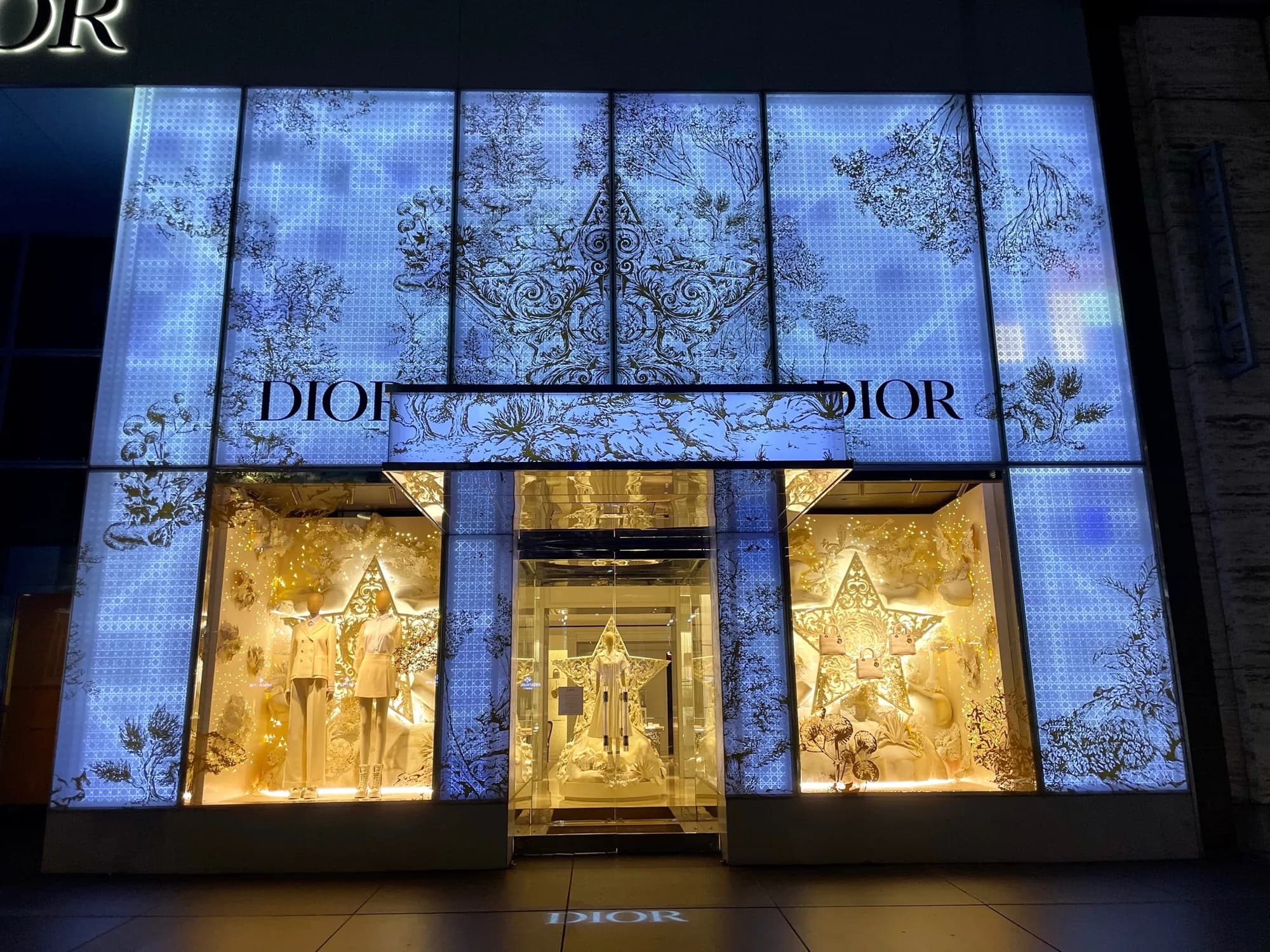 Dior 57th Street facade wrapped in backlit blue-and-white botanical panels, 2021, at night