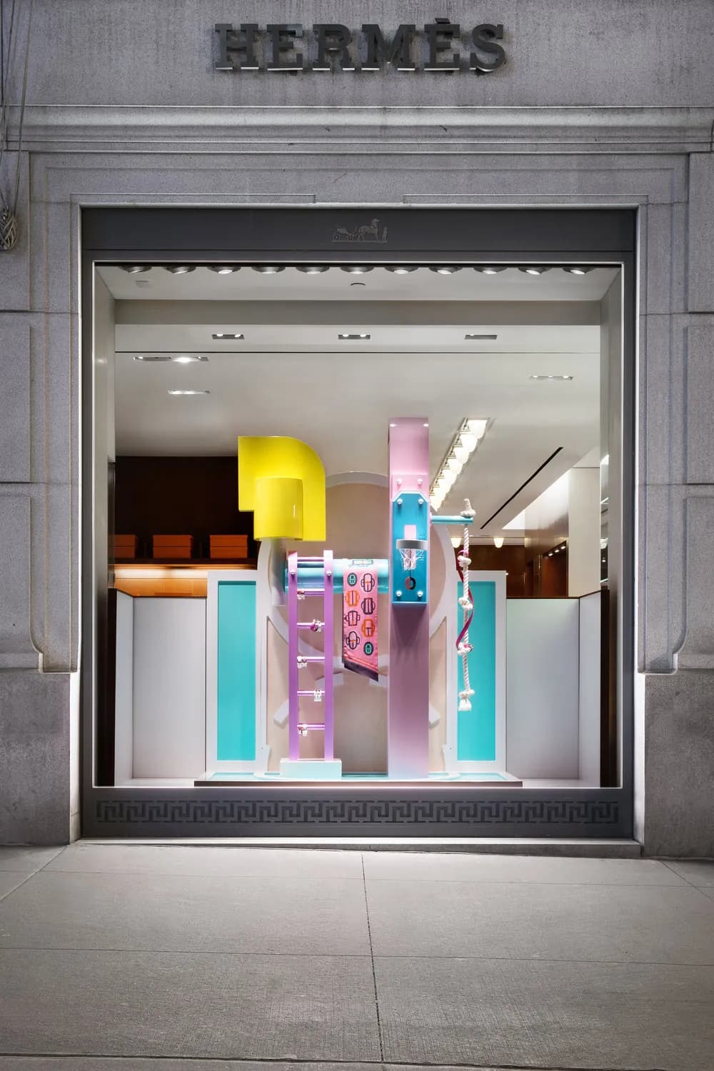 Hermès window framed in stone with pink, yellow and turquoise abstract sculptures