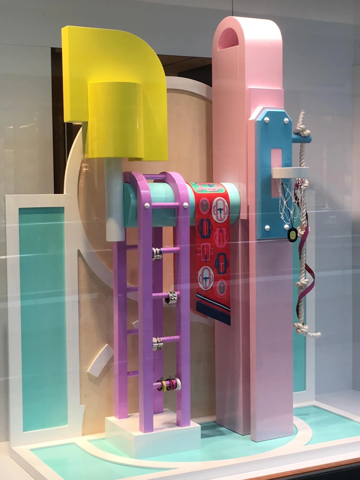 Close view of a Hermès window sculpture in pink, yellow and turquoise with Hermès lettering